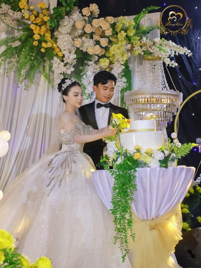 Nghi thức cắt bánh kem cưới trên tháp đèn pha lê sang trọng.