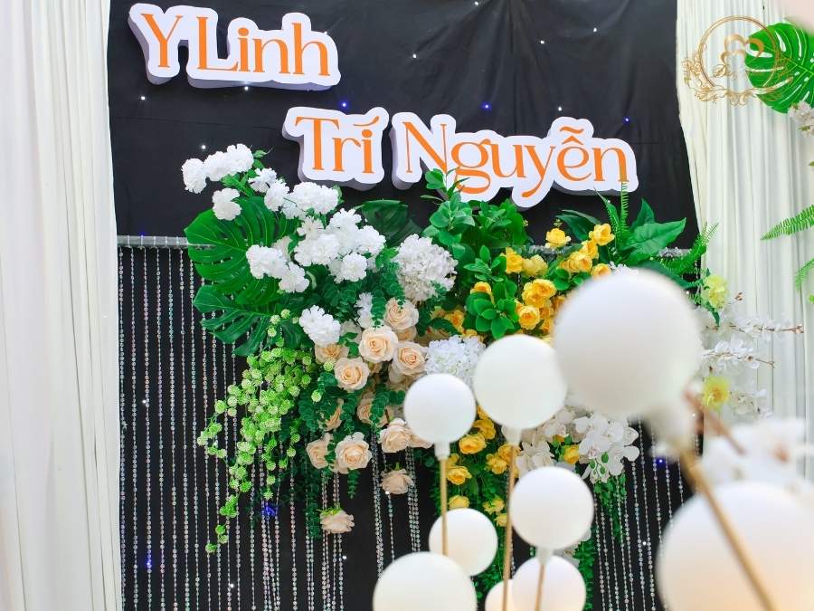 Cận cảnh tên dâu rể Y Linh & Trí Nguyễn chữ nổi 3D trên nền nhung đen, đèn bulb.