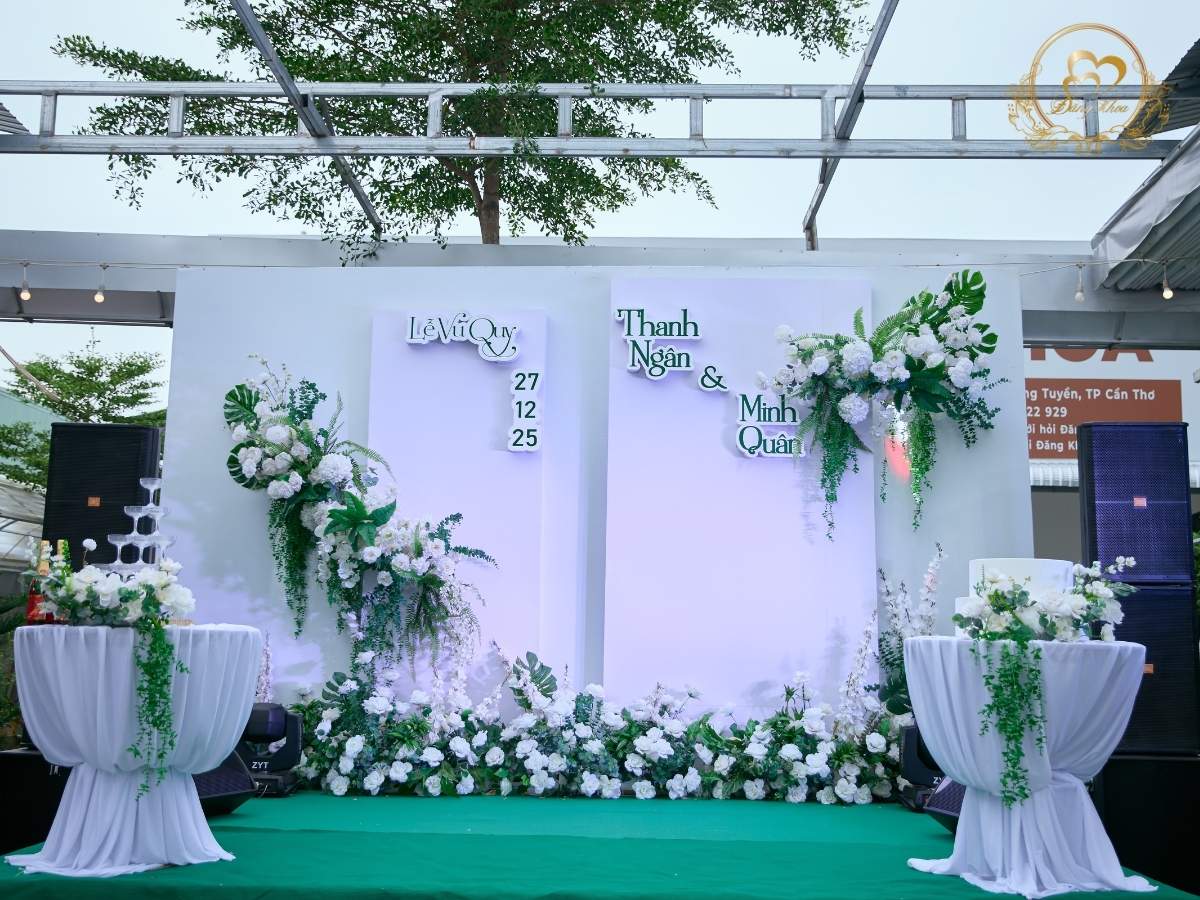 Sân khấu cưới garden tone trắng xanh, lá cây hiện đại.