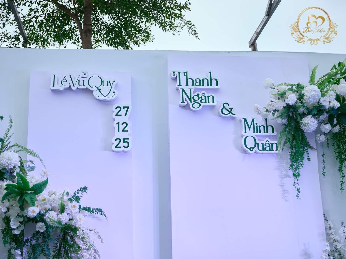 Cận cảnh chi tiết trang trí chữ cô dâu chú rể và ngày cưới 27.12.2025 trên phông nền.