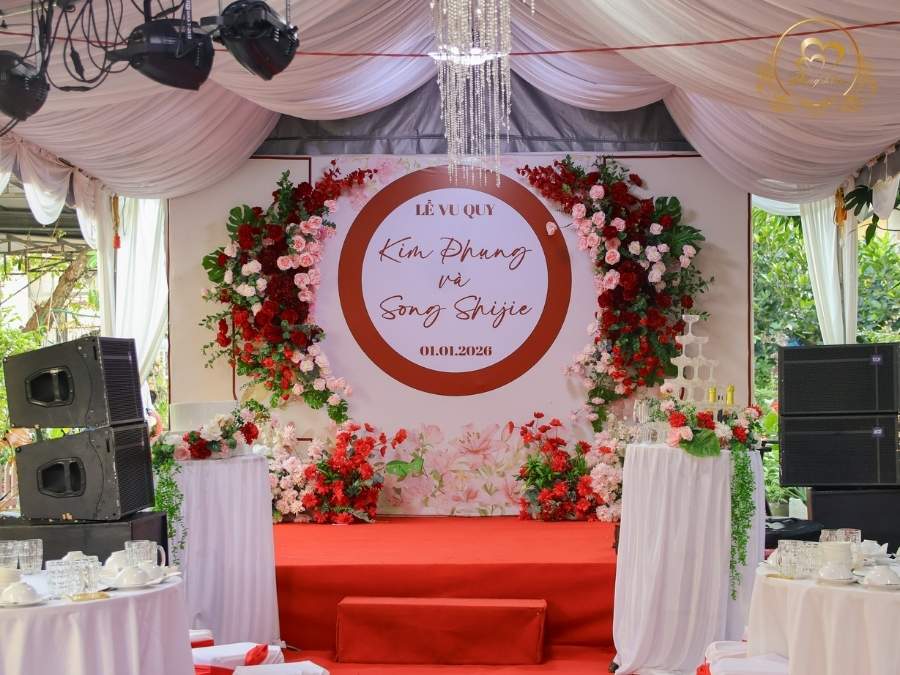 Sân khấu tiệc cưới Lễ Vu Quy trang trí tone đỏ lãng mạn và đèn chùm pha lê.