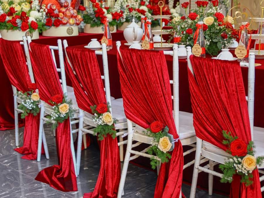 Trang trí ghế Tiffany đám cưới: vải voan đỏ kết hợp hoa hồng cài lưng ghế.
