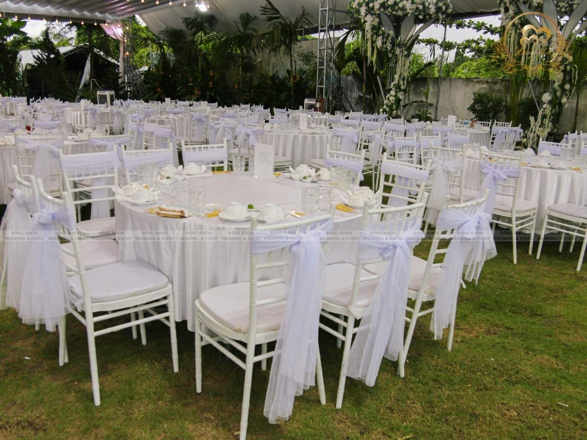 Setup bàn tiệc cưới không gian mở ghế tiffany trắng thắt nơ voan tinh tế.