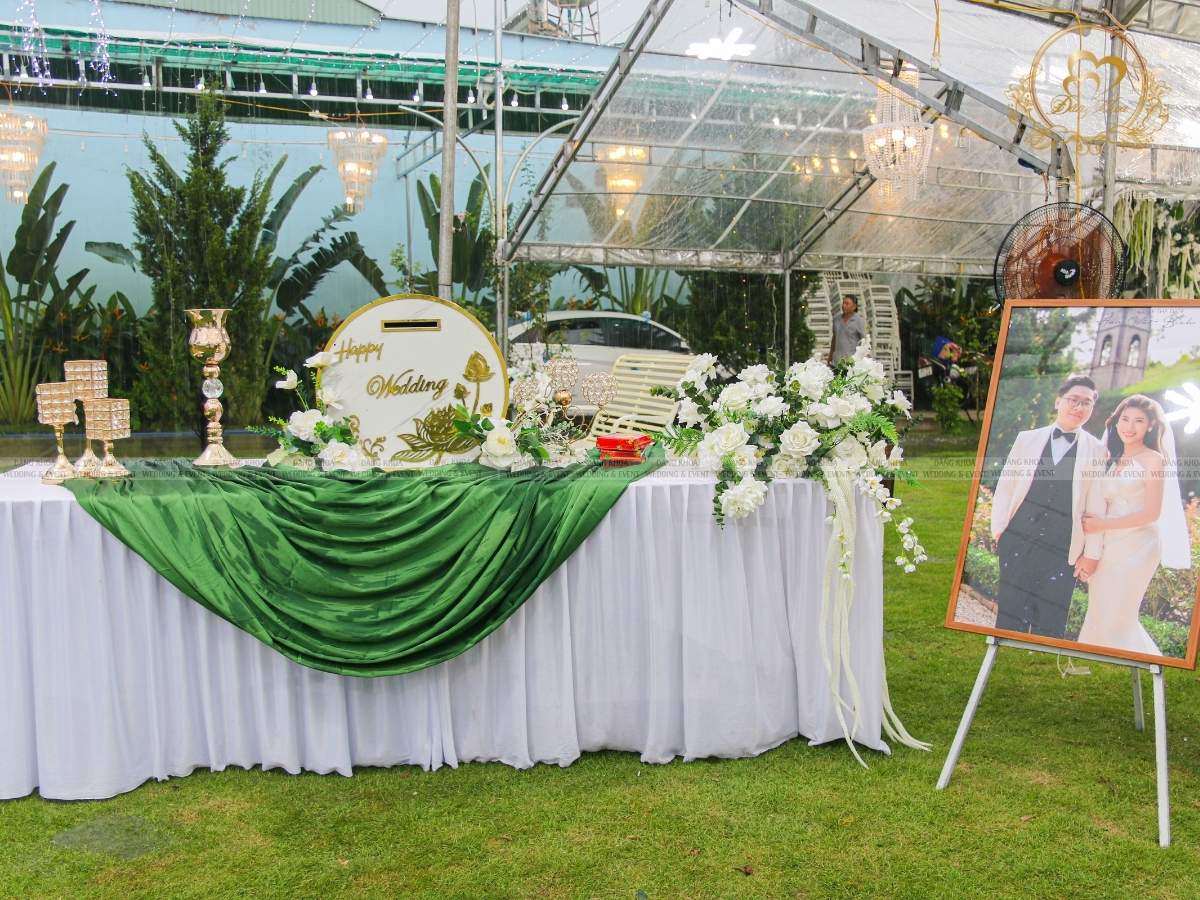 Trang trí bàn gallery đón khách tone trắng xanh lá với khăn trải và hoa tươi.