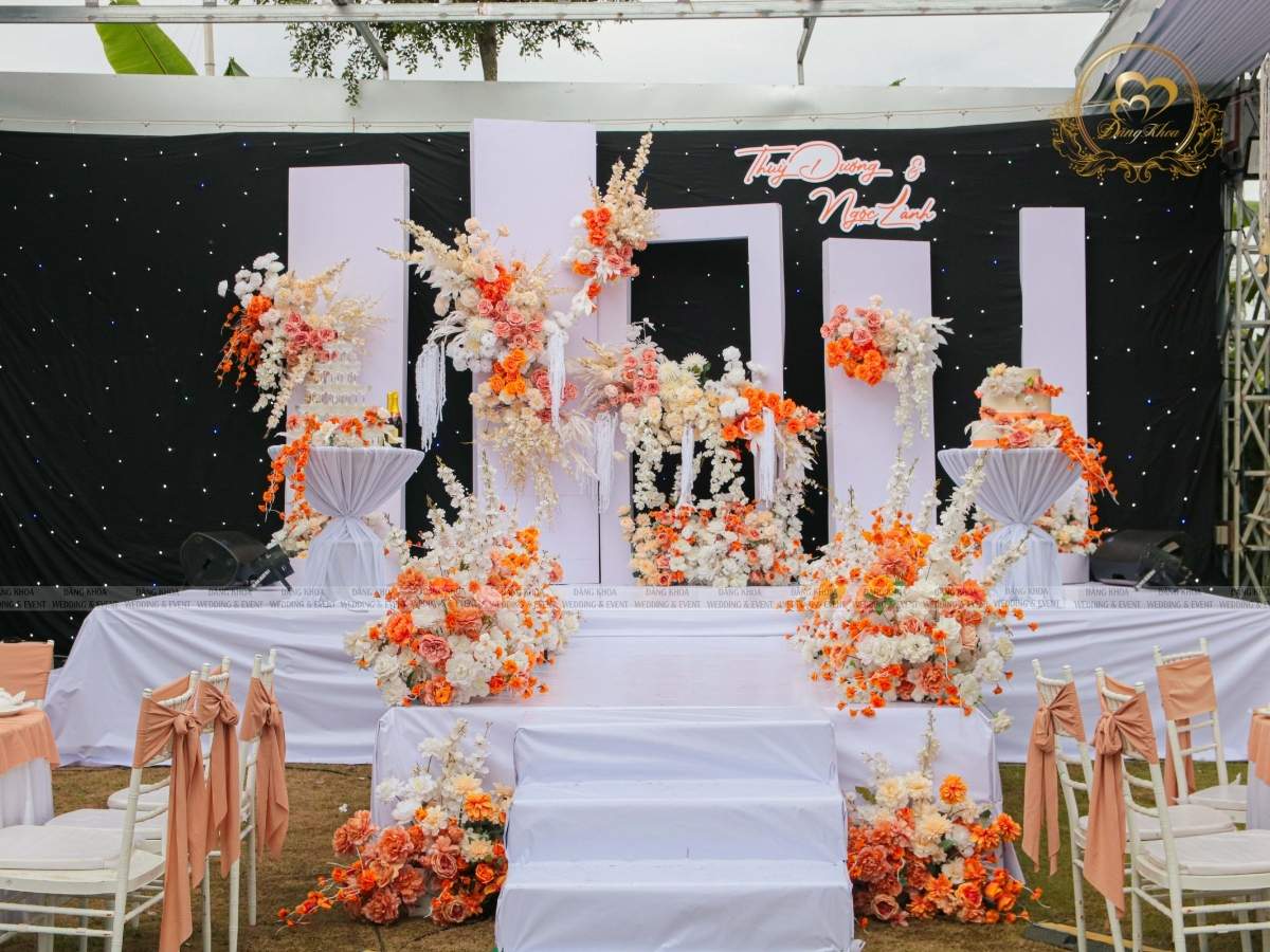Sân khấu cưới tiệc ngoài trời tone trắng cam.