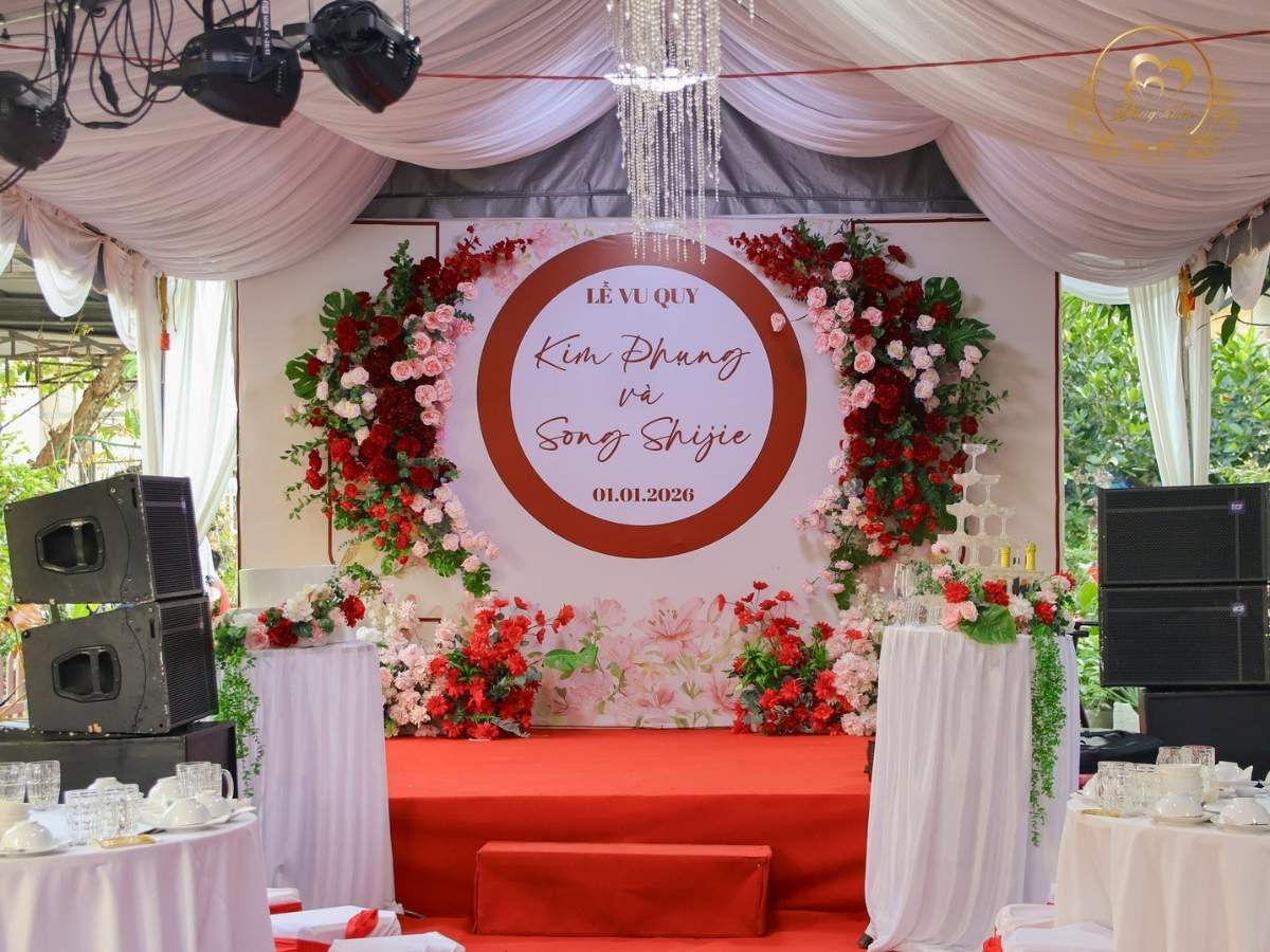 Sân khấu Lễ Vu Quy tone đỏ trắng & backdrop tròn hoa lụa.