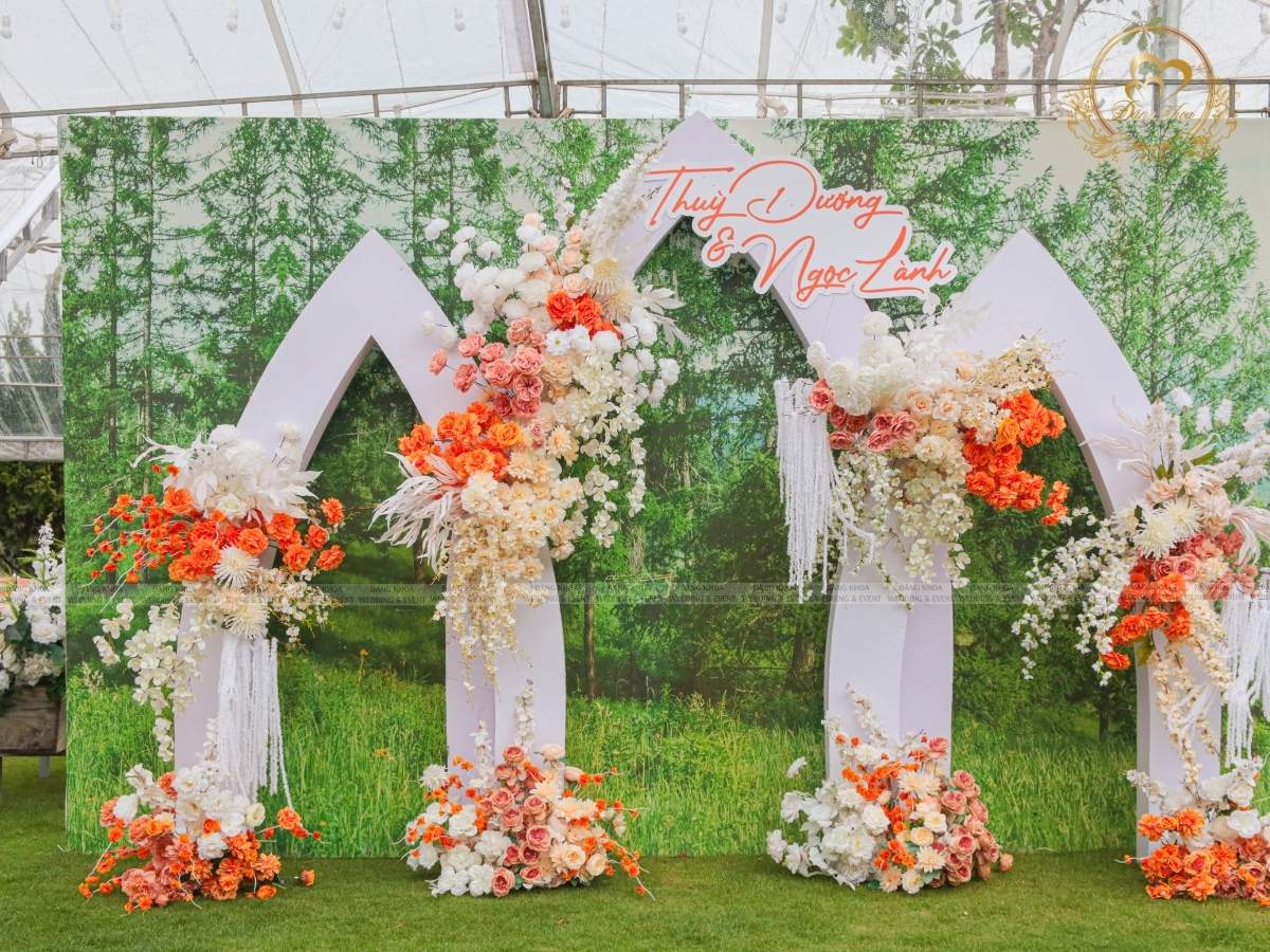 Cận cảnh backdrop phông chụp hình cưới tone trắng cam nền vườn rừng cây xanh.