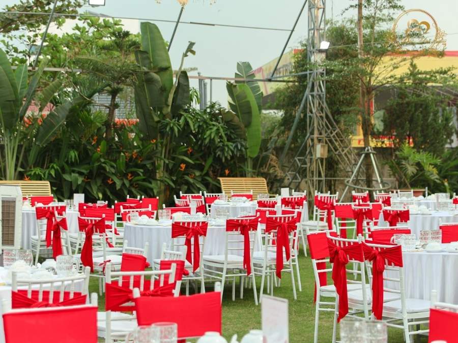 Setup bàn tiệc cưới ngoài trời ghế Tiffany thắt nơ đỏ.